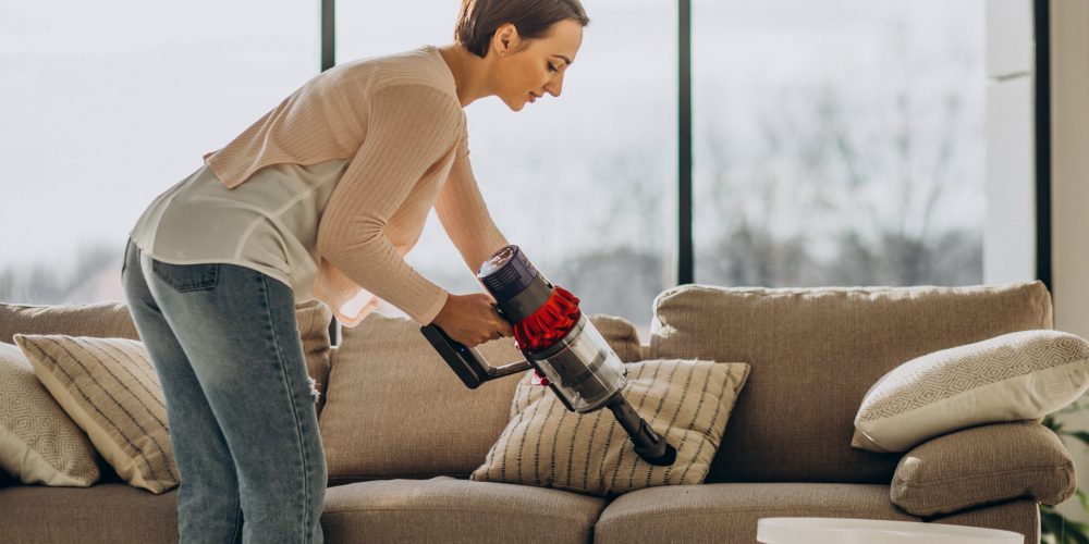 Young woman with rechargeable vacuum cleaner cleaning at home